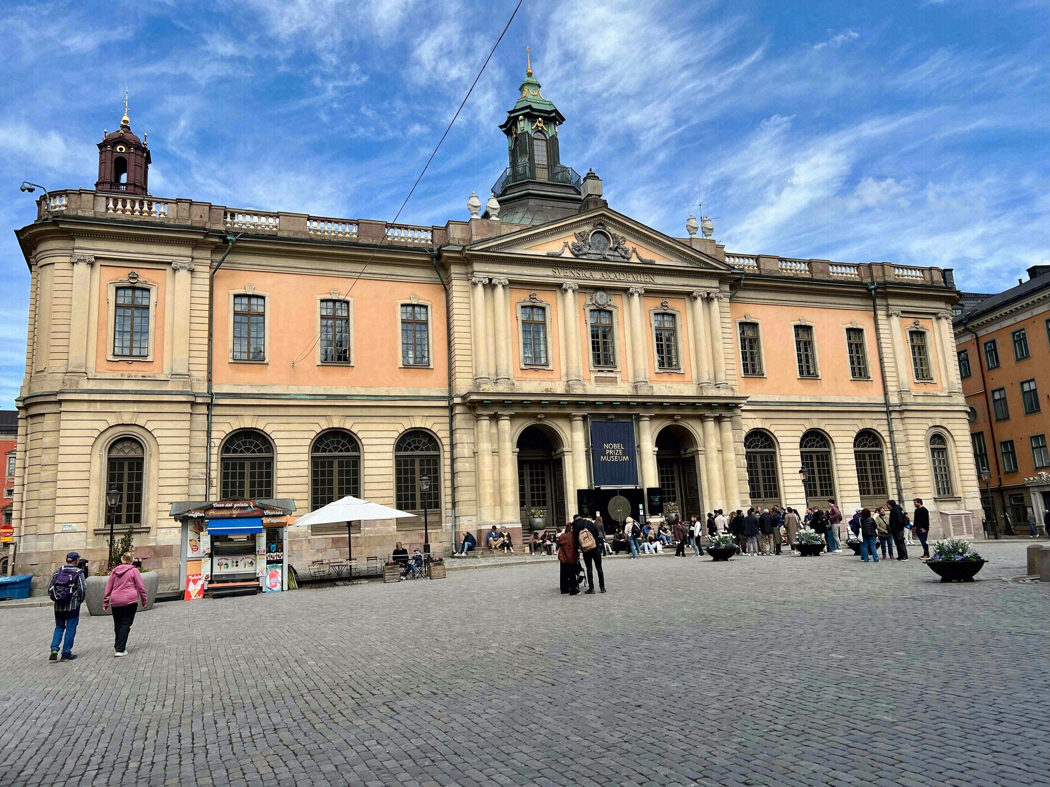 Fassade des Nobel Prize Museum am Stortorget in Gamla Stan mit dem markanten orangefarbenen Barockbau der Börse.